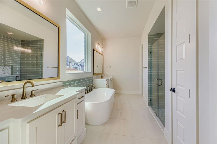 Full bathroom with a soaking tub, two vanities, a shower stall, light tile patterned floors, and recessed lighting
