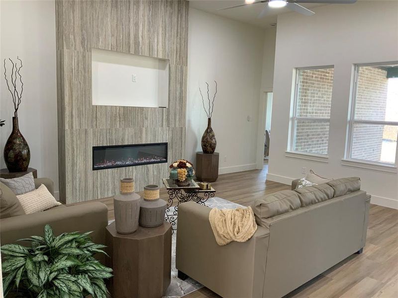 Living room featuring light wood finished floors, a fireplace, and ceiling fan Living room featuring light wood finished floors, a fireplace, and ceiling fan