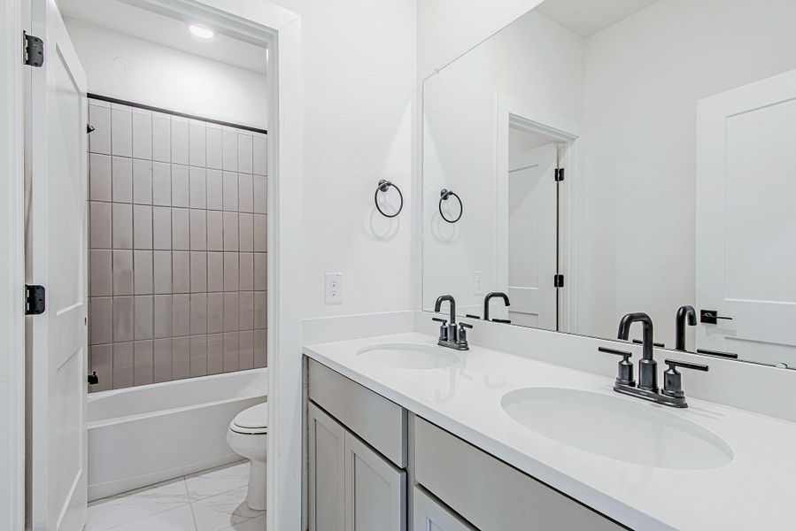Secondary bathroom with a dual vanity and sleek tiled shower