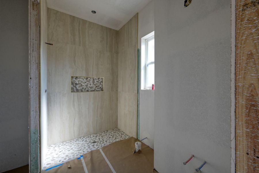 This en-suite bathroom offers comfort, flexibility, and custom-level attention to detail with floor to ceiling tile in the walk-in shower.