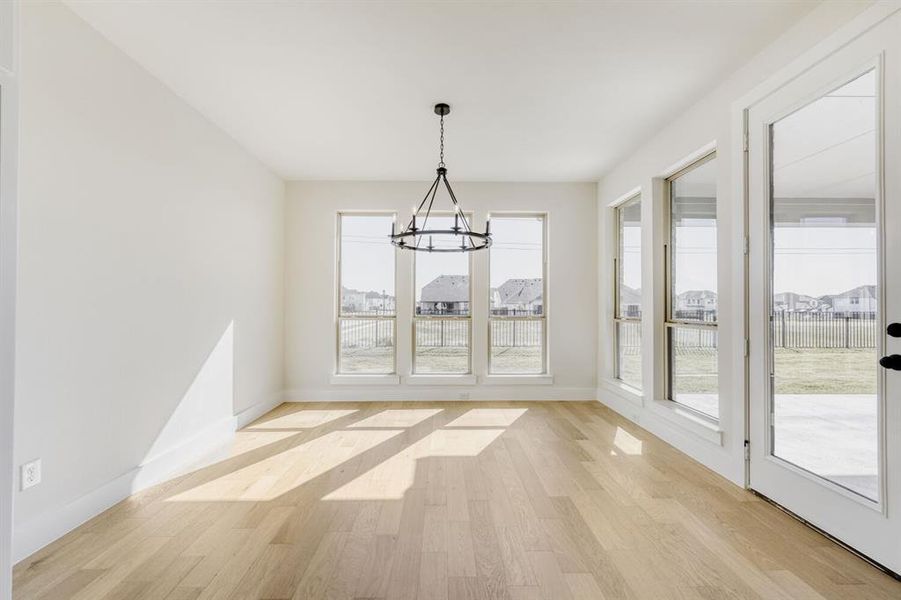 Unfurnished dining area featuring light wood-style floors, a chandelier, and a residential view
