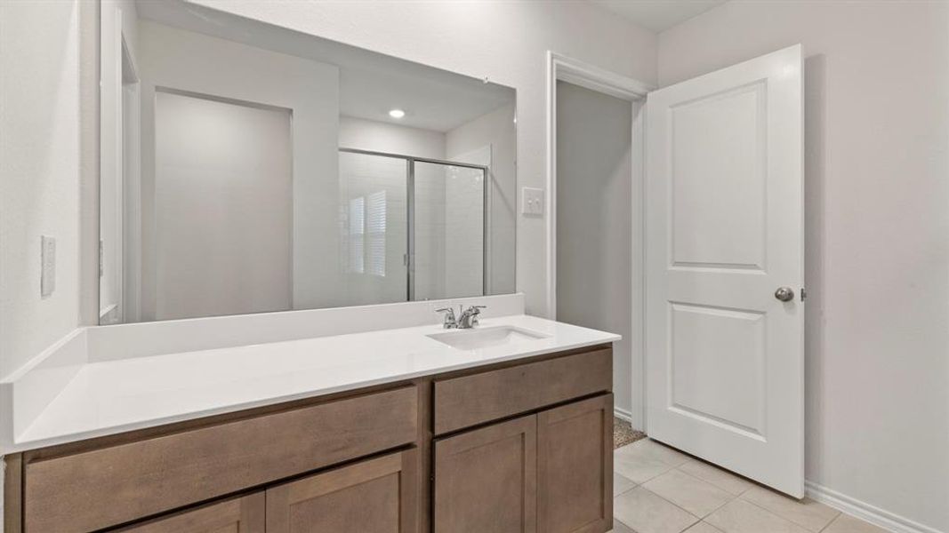 Full-width vanity mirror reflecting a white-tiled shower with glass enclosure
