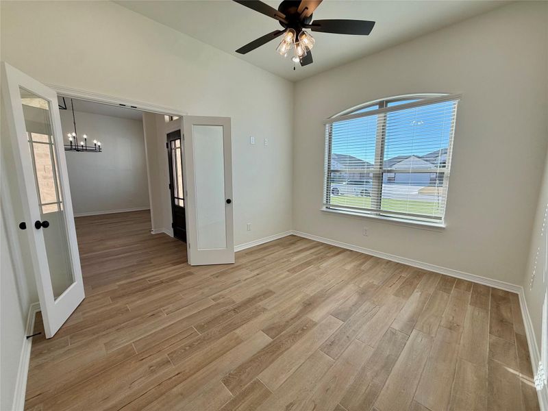 Unfurnished bedroom with light wood-style floors, ceiling fan, french doors, and suspended lighting