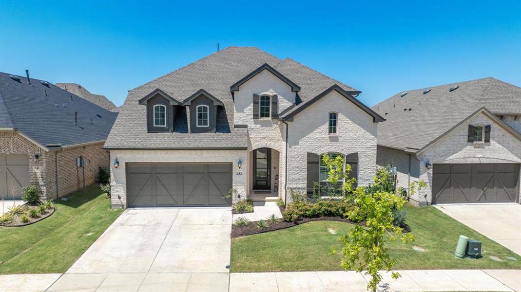 French country style house with a front lawn and a garage