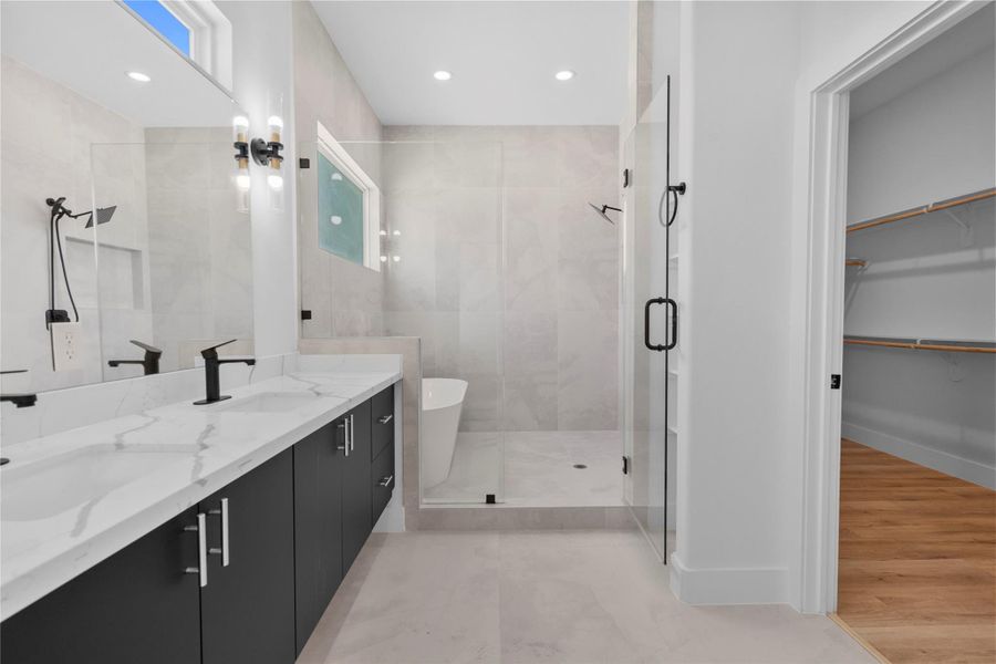 Bath with an oversized glass-enclosed shower, dual-sink vanity, freestanding tub and spacious walk-in closet Bath with an oversized glass-enclosed shower, dual-sink vanity, freestanding tub and spacious walk-in closet