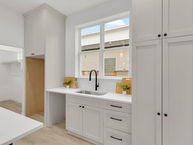 Kitchen with white cabinets, backsplash, light wood-type flooring, and sink