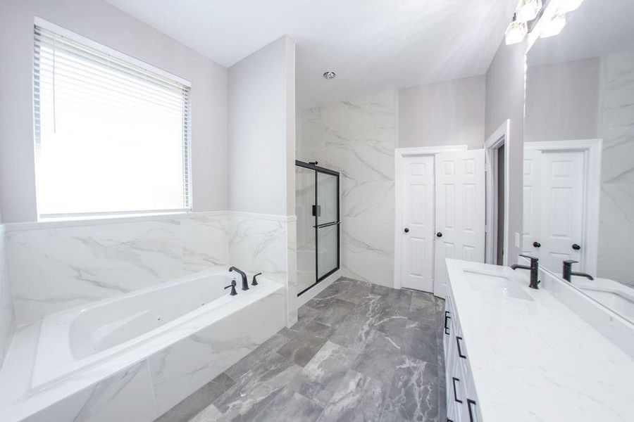 Bathroom with dark marble finish flooring, vanity, a garden tub, and a marble finish shower Bathroom with dark marble finish flooring, vanity, a garden tub, and a marble finish shower