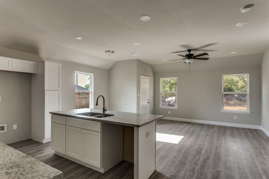Kitchen featuring white cabinetry, light stone counters, dark wood-style flooring, open floor plan, and recessed lighting