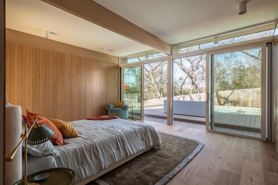 Bedroom with access to outside, beamed ceiling, hardwood / wood-style flooring, expansive windows, and wood walls