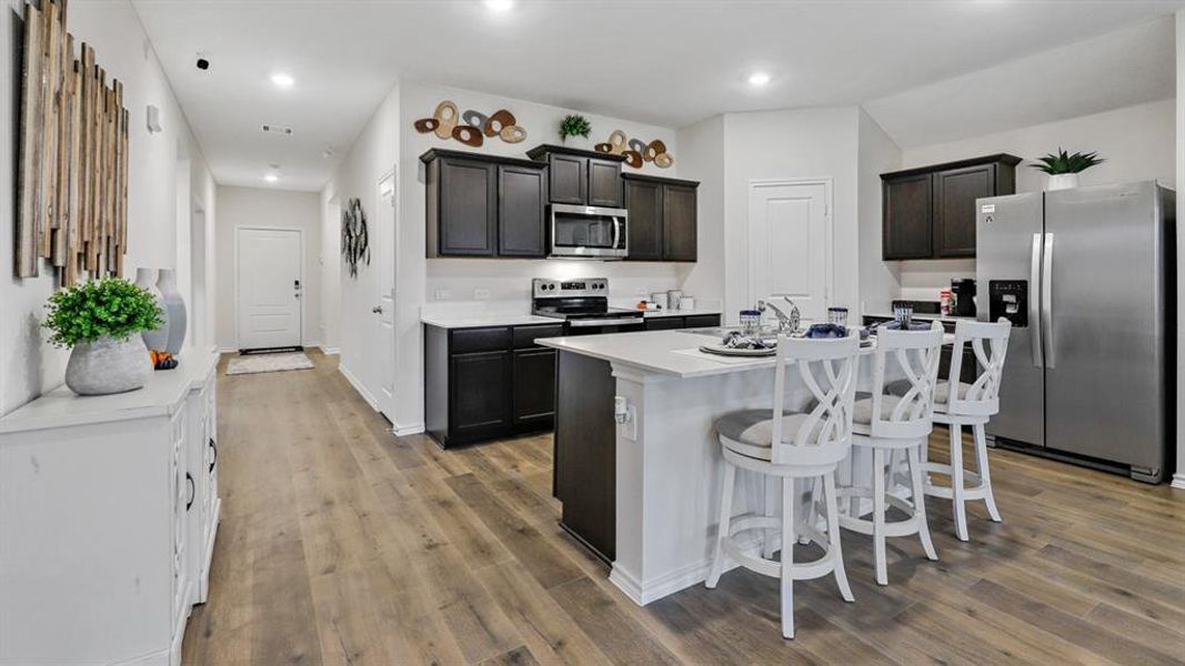 Kitchen featuring stainless steel appliances, a breakfast bar area, a kitchen island with sink, light wood-type flooring, and recessed lighting Kitchen featuring stainless steel appliances, a breakfast bar area, a kitchen island with sink, light wood-type flooring, and recessed lighting