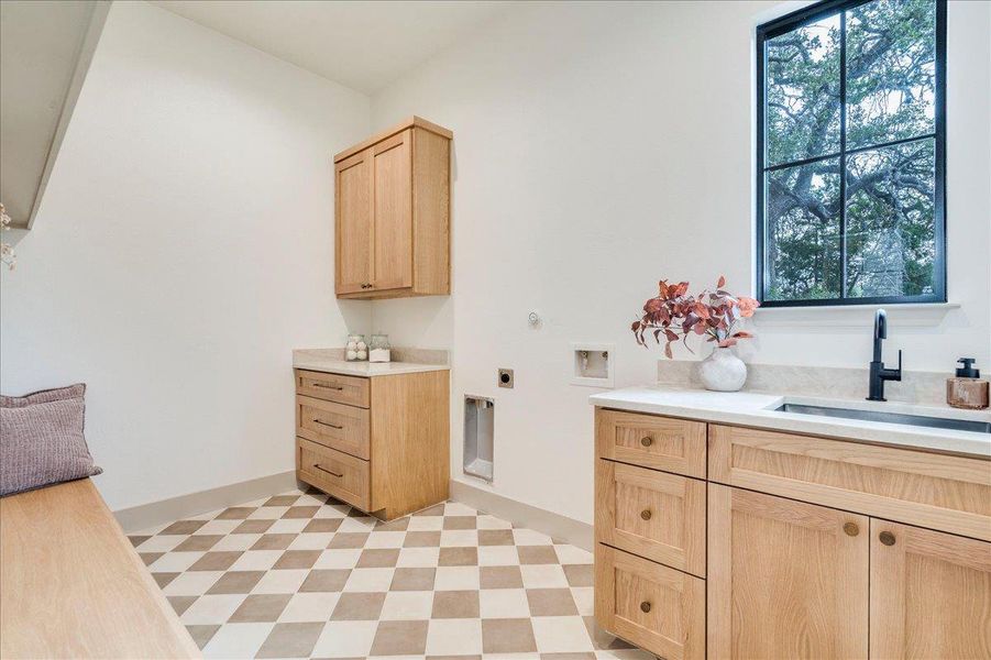 Practical and organized, this laundry room features durable tile flooring and abundant cabinet storage.