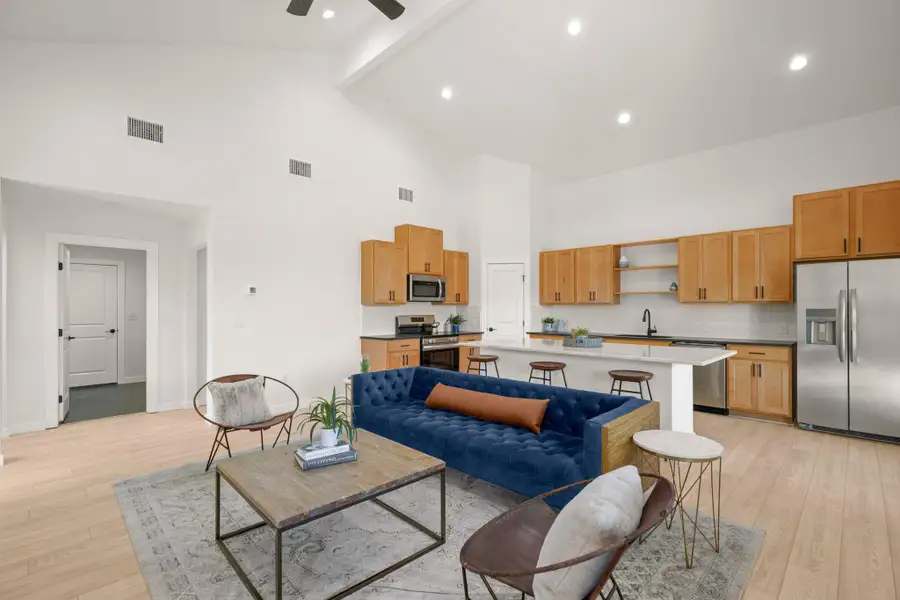 Living area with beamed ceiling, light wood-style floors, high vaulted ceiling, recessed lighting, and a ceiling fan