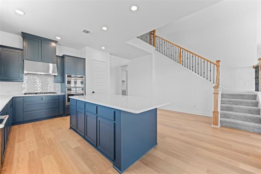 Kitchen featuring a kitchen island, light hardwood / wood-style floors, tasteful backsplash, and stainless steel appliances