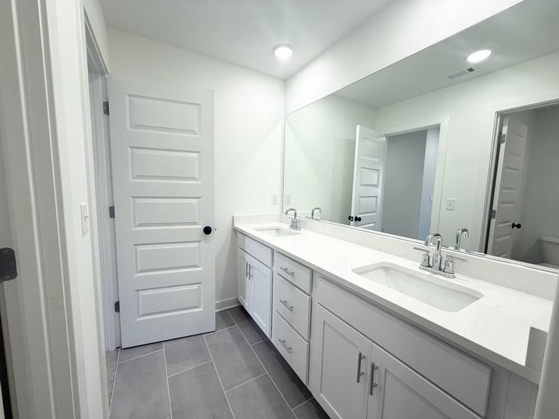 Bathroom with double vanity, dark tile patterned floors, and recessed lighting