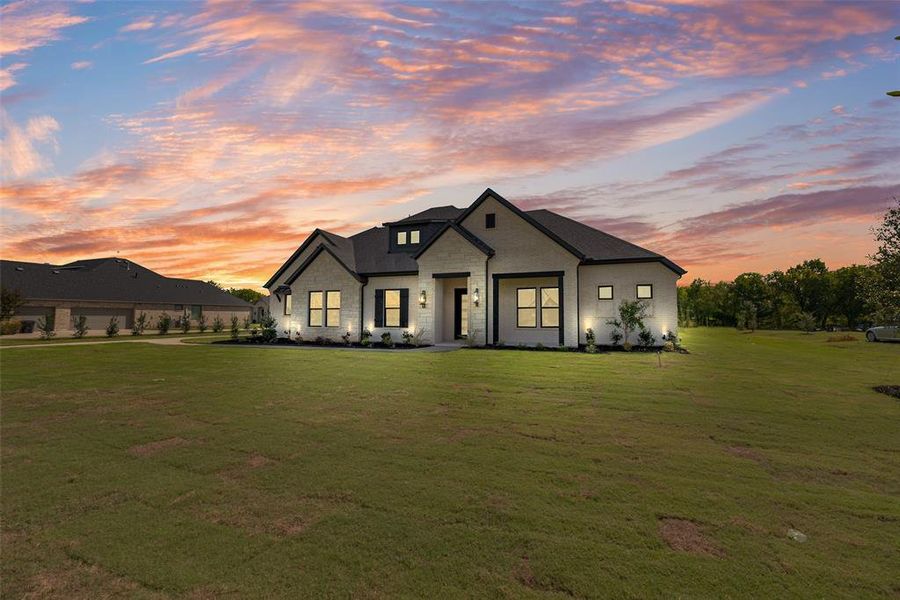 Modern farmhouse with stone siding and a front lawn