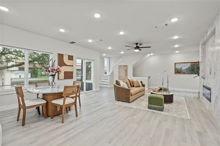 Living area with healthy amount of natural light, recessed lighting, a tile fireplace, stairs, and light wood-style flooring Living area with healthy amount of natural light, recessed lighting, a tile fireplace, stairs, and light wood-style flooring