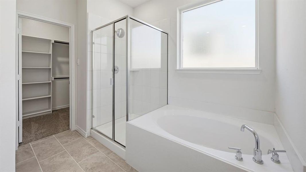 Full bath featuring a garden tub, a stall shower, a spacious closet, and light tile patterned floors