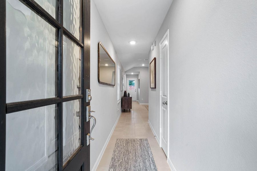 A stylish dark-wood front door featuring elegant glass panels opens into a bright, welcoming hallway, setting a sophisticated tone from the moment you arrive.