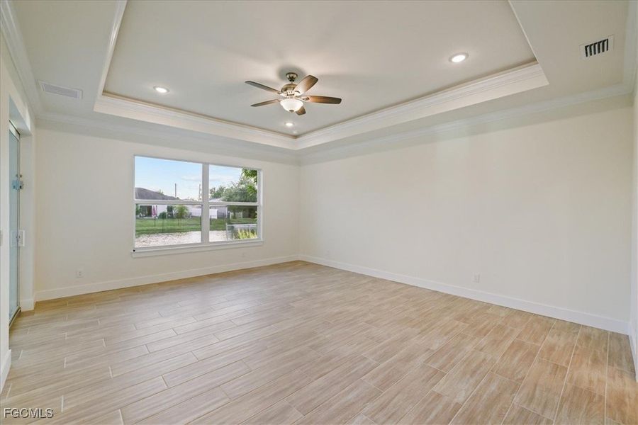 Unfurnished room with ornamental molding, a tray ceiling, wood finish floors, ceiling fan, and recessed lighting