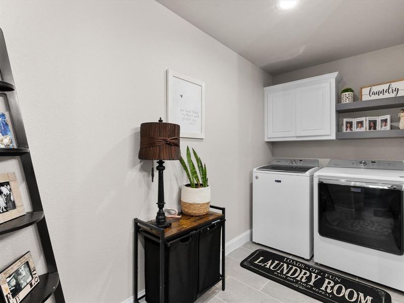 Washroom with washer and clothes dryer, light tile patterned floors, cabinet space, and baseboards