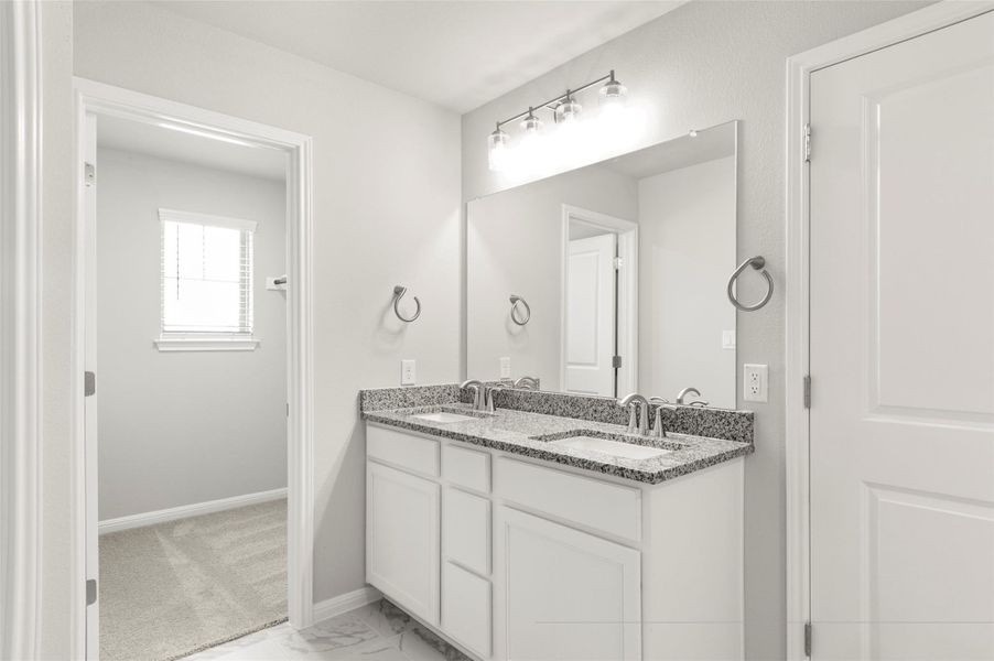 Full bath featuring double vanity, baseboards, and marble look tiles