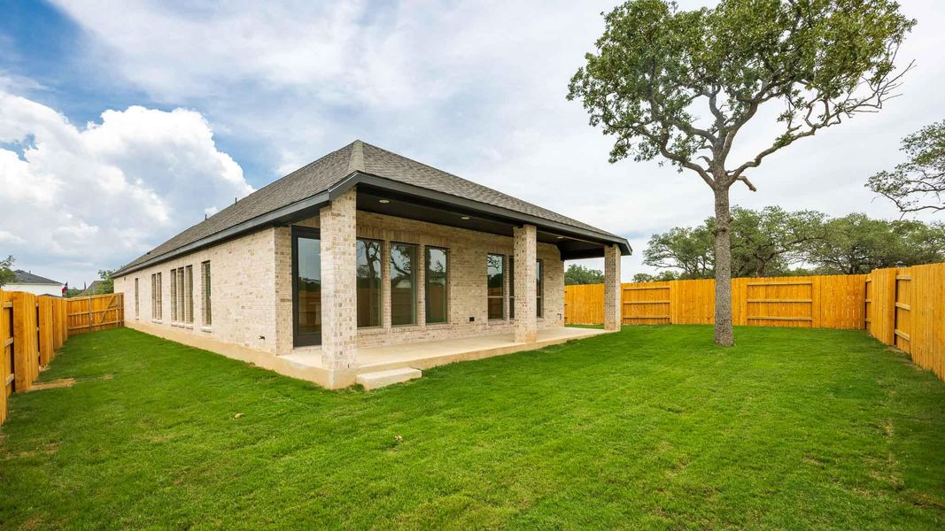 Back of house with brick siding, a patio, a fenced backyard, and roof with shingles