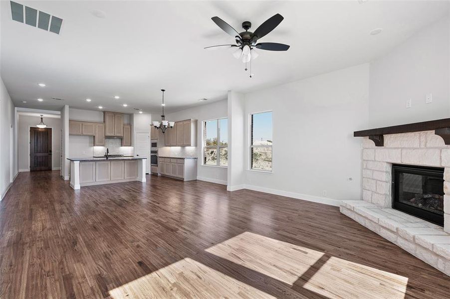Unfurnished living room featuring recessed lighting, a chandelier, dark wood finished floors, a ceiling fan, and a fireplace