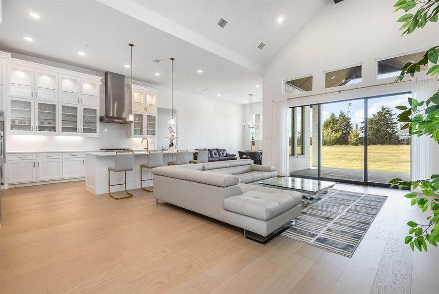 Living area featuring light wood-style floors, high vaulted ceiling, recessed lighting, and beam ceiling