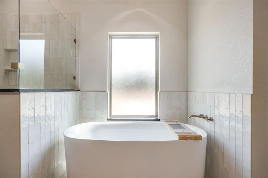 Full bath featuring a soaking tub, tile walls, a tile shower, and wainscoting Full bath featuring a soaking tub, tile walls, a tile shower, and wainscoting