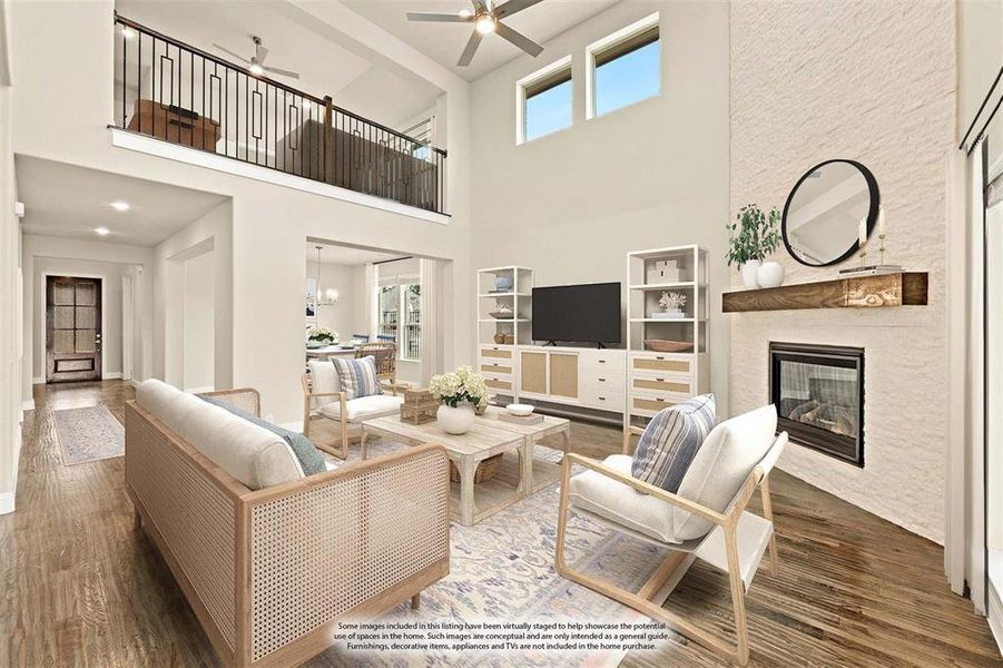 Living room with a fireplace, ceiling fan, a towering ceiling, wood finished floors, and a chandelier