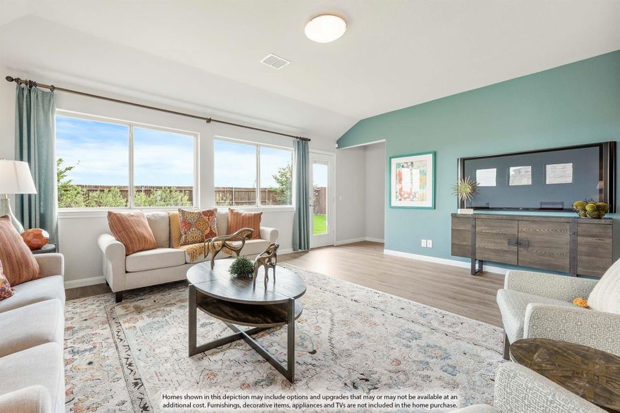 Living room with teal accent wall, hardwood floors, large windows, and round coffee table Living room with teal accent wall, hardwood floors, large windows, and round coffee table