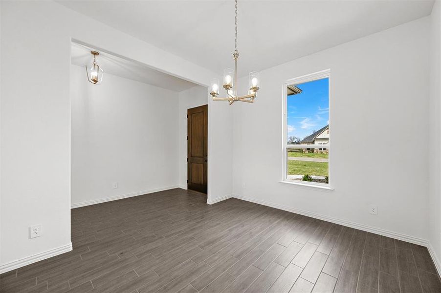 Unfurnished room with a notable chandelier and dark hardwood / wood-style flooring