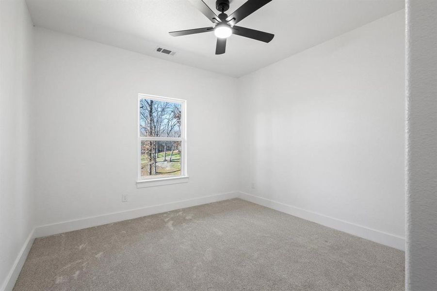 Empty room featuring ceiling fan and carpet floors