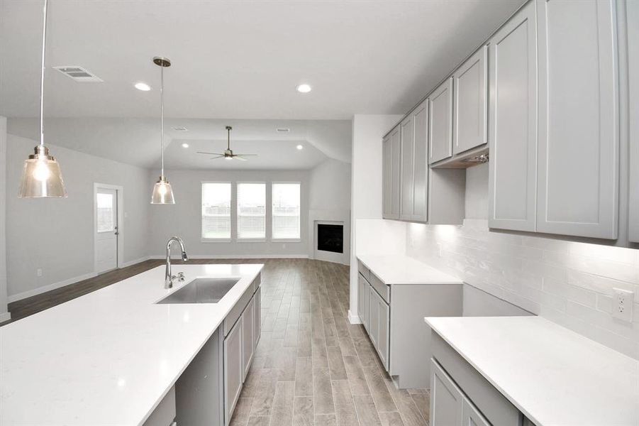 Culinary haven, featuring granite countertops, a tile backsplash, stainless steel appliances, 42” upper cabinets, and undercabinet lighting. Sample photo of completed home with similar floor plan. As-built interior colors and selections may vary.