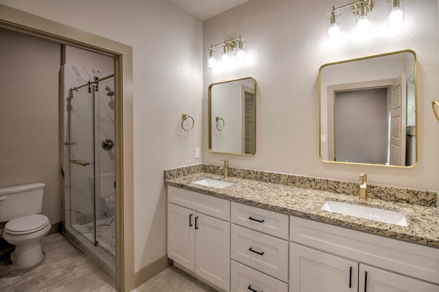 Bathroom with a marble finish shower, double vanity, and a textured wall