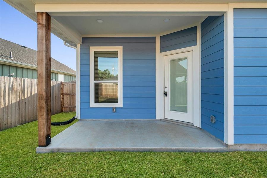 View of exterior entry with a lawn and a patio area