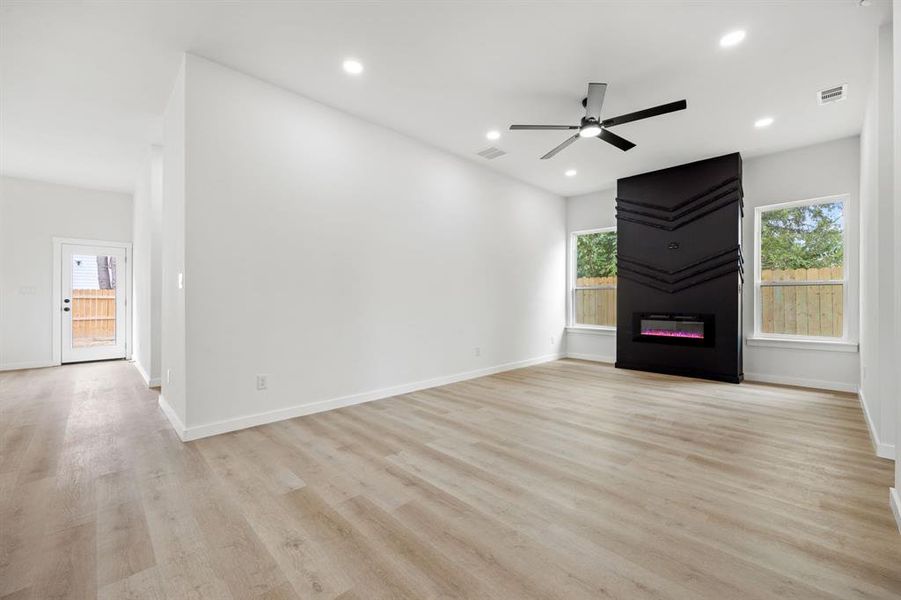 Unfurnished living room with a fireplace, a healthy amount of sunlight, light wood-type flooring, and ceiling fan