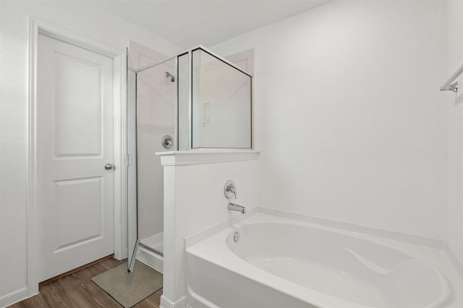 An additional view of the Primary Bath Oasis featuring a glass encased walk-in shower with tile surround, separate soaking tub, and oversized window to bring in tons of natural light.