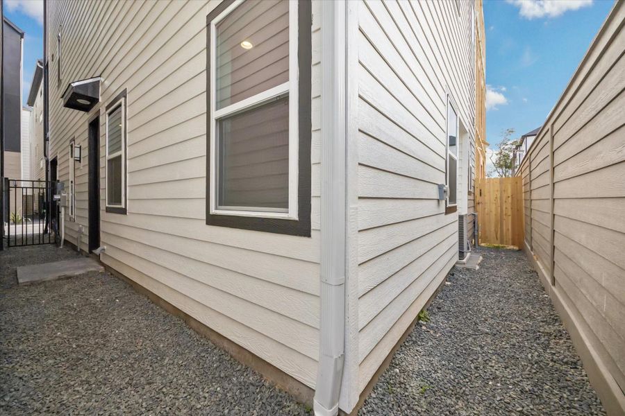 Rear gravel area showcases a low-maintenance outdoor space with a secure gate, perfect for privacy and versatility.