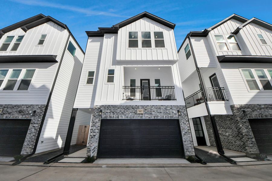 Modern three-story townhouse with a sleek design, featuring a white exterior accented by brickwork. Includes a two-car garage and a small balcony, offering a stylish urban living option. Modern three-story townhouse with a sleek design, featuring a white exterior accented by brickwork. Includes a two-car garage and a small balcony, offering a stylish urban living option.
