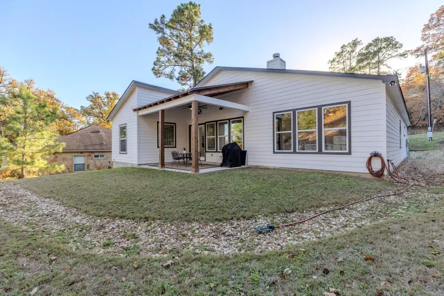 Rear view of house with a patio, a lawn, and a chimney