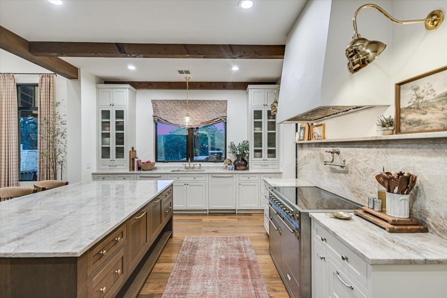 Kitchen with white cabinetry, light stone counters, beam ceiling, and recessed lighting Kitchen with white cabinetry, light stone counters, beam ceiling, and recessed lighting
