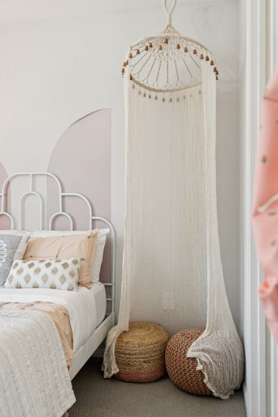 A white crib with a white cloth from it.