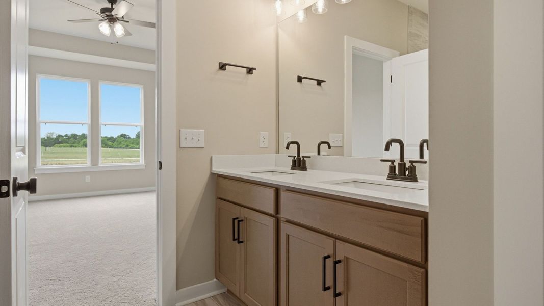 Bathroom with dual vanity leading to primary suite Bathroom with dual vanity leading to primary suite