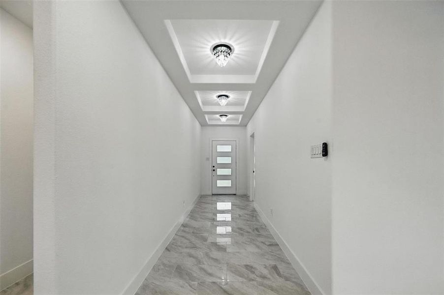 Hallway featuring light marble finish flooring and baseboards