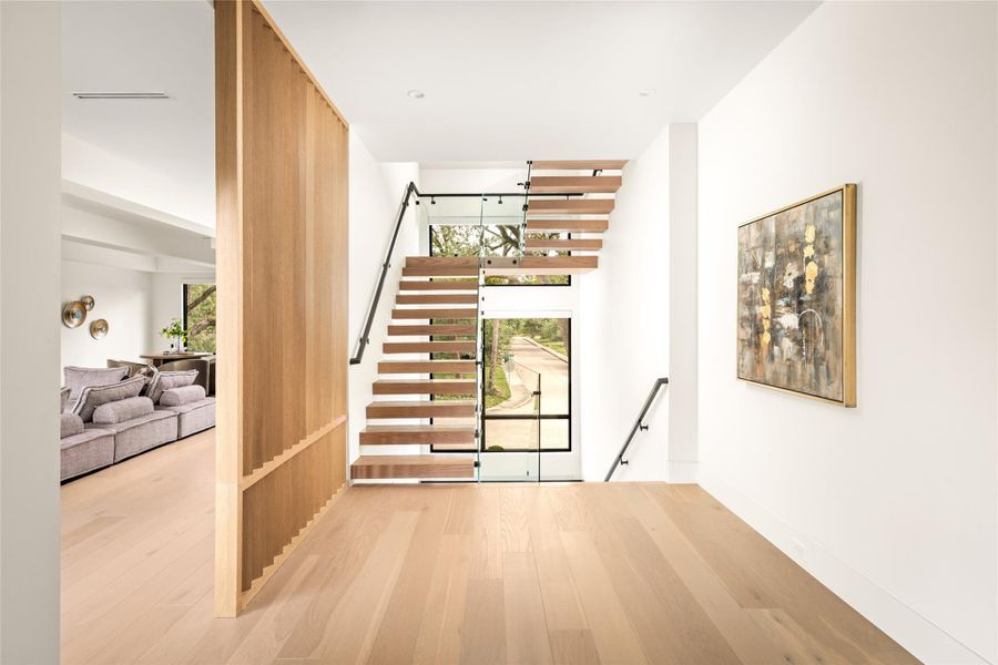 Upper-level landing overlooking the floating staircase, filled with natural light and warm wood detailing.