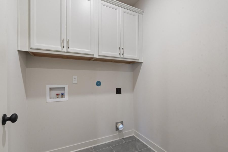 White shaker cabinetry with modern hardware, durable tile flooring, and utility hookups White shaker cabinetry with modern hardware, durable tile flooring, and utility hookups