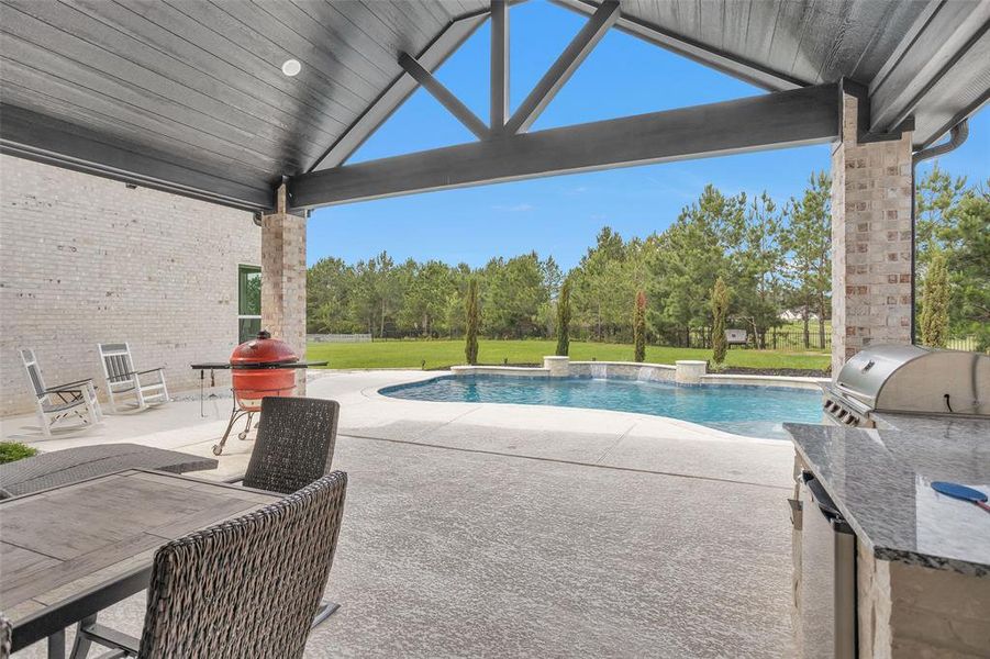 In the back of the home is the enormous covered cool-decking patio, also around the pool, with can lighting and ceiling fan.