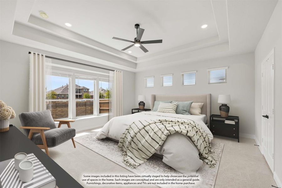 Spacious master bedroom with tray ceiling, ceiling fan, large windows, and neutral carpet flooring Spacious master bedroom with tray ceiling, ceiling fan, large windows, and neutral carpet flooring