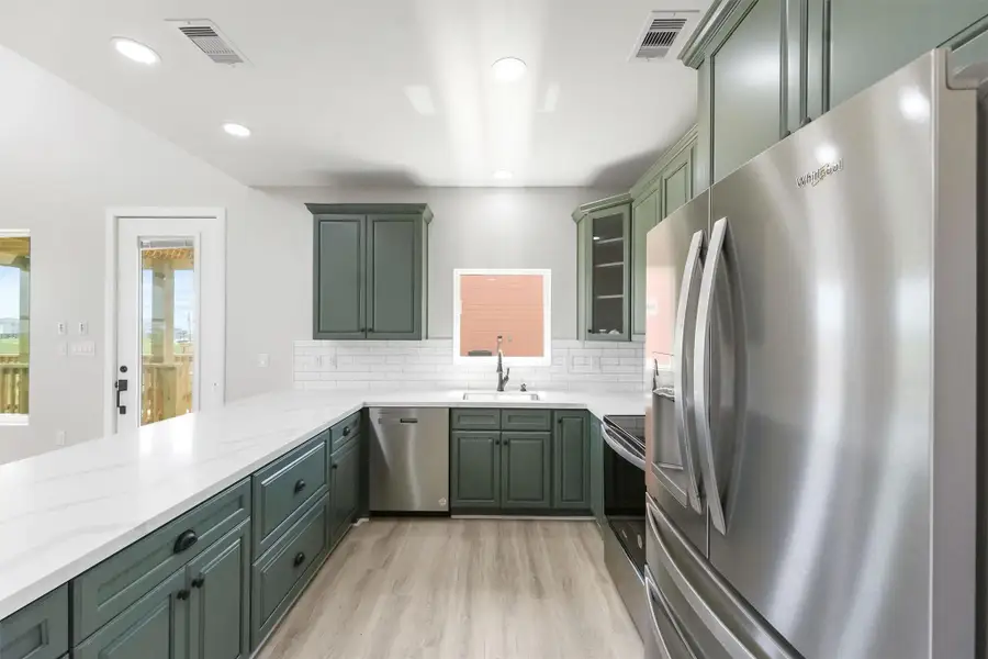 This kitchen features modern green cabinetry, stainless steel appliances, and a bright, open layout. It includes a large countertop, subway tile backsplash, and recessed lighting, creating a stylish and functional space. This kitchen features modern green cabinetry, stainless steel appliances, and a bright, open layout. It includes a large countertop, subway tile backsplash, and recessed lighting, creating a stylish and functional space.